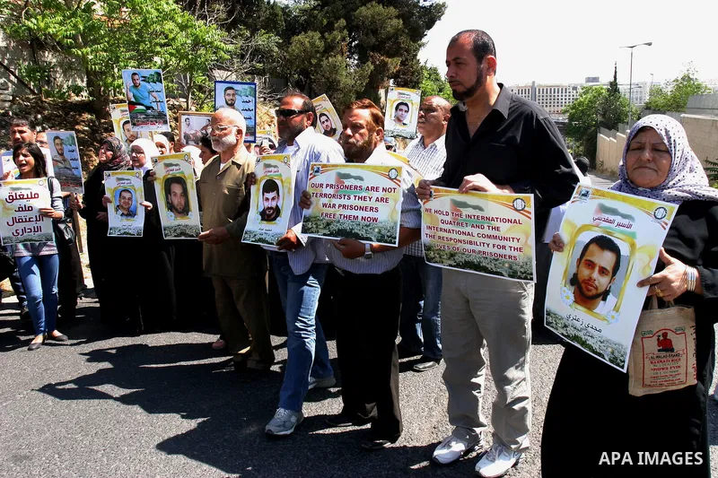 Palestinian protesters hold slogans and portraits of Palestinian prisoners, held in Israeli jails, during a demonstration in east Jerusalem on May 7, 2012 in solidarity with the prisoners. At least 1,550 imprisoned Pales...