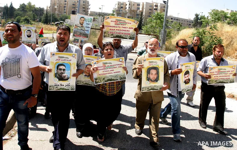 Palestinian protesters hold slogans and portraits of Palestinian prisoners, held in Israeli jails, during a demonstration in east Jerusalem on May 7, 2012 in solidarity with the prisoners. At least 1,550 imprisoned Pales...