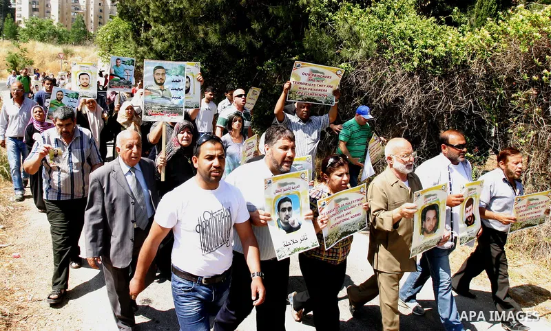 Palestinian protesters hold slogans and portraits of Palestinian prisoners, held in Israeli jails, during a demonstration in east Jerusalem on May 7, 2012 in solidarity with the prisoners. At least 1,550 imprisoned Pales...