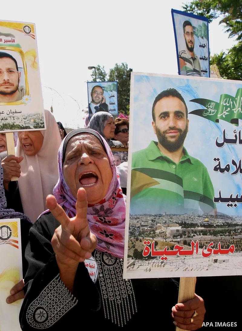 Palestinian protesters hold slogans and portraits of Palestinian prisoners, held in Israeli jails, during a demonstration in east Jerusalem on May 7, 2012 in solidarity with the prisoners. At least 1,550 imprisoned Pales...