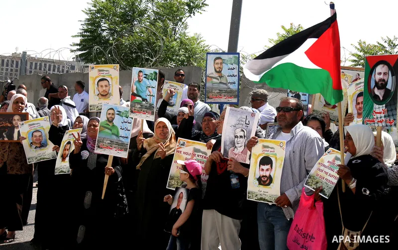 Palestinian protesters hold slogans and portraits of Palestinian prisoners, held in Israeli jails, during a demonstration in east Jerusalem on May 7, 2012 in solidarity with the prisoners. At least 1,550 imprisoned Pales...