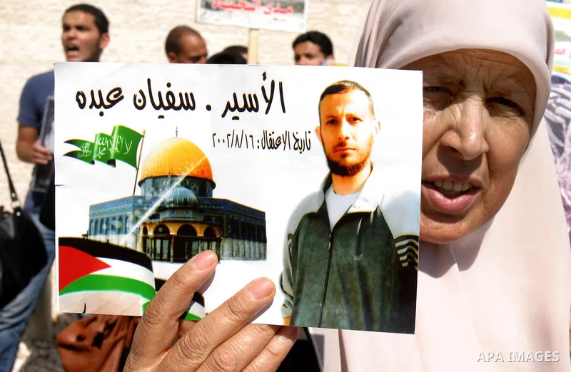 Palestinian protesters hold slogans and portraits of Palestinian prisoners, held in Israeli jails, during a demonstration in east Jerusalem on May 7, 2012 in solidarity with the prisoners. At least 1,550 imprisoned Pales...