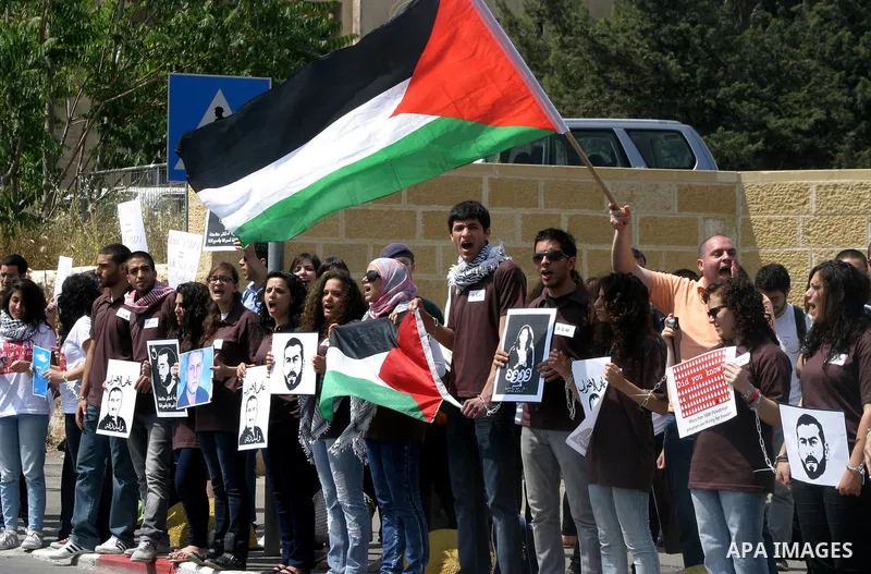 Palestinian protesters hold slogans and portraits of Palestinian prisoners, held in Israeli jails, during a demonstration in east Jerusalem on May 8, 2012 in solidarity with the prisoners. At least 1,550 imprisoned Pales...