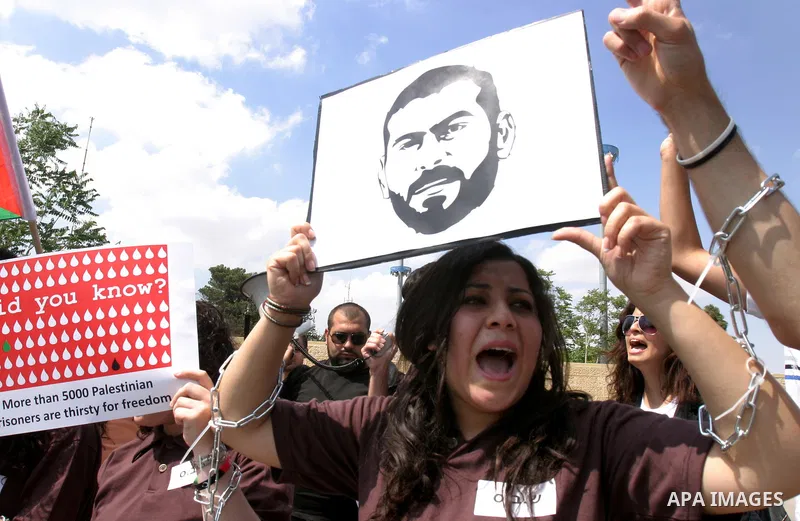 Palestinian protesters hold slogans and portraits of Palestinian prisoners, held in Israeli jails, during a demonstration in east Jerusalem on May 8, 2012 in solidarity with the prisoners. At least 1,550 imprisoned Pales...