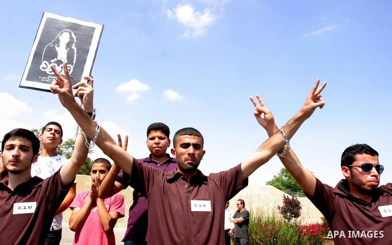 Palestinian protesters hold slogans and portraits of Palestinian prisoners, held in Israeli jails, during a demonstration in east Jerusalem on May 8, 2012 in solidarity with the prisoners. At least 1,550 imprisoned Pales...