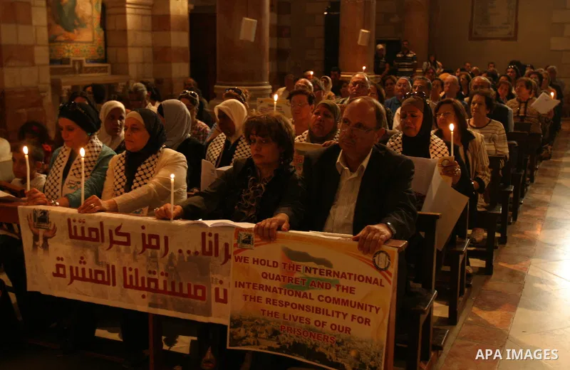 Palestinian Christians and Muslims hold pictures of incarcerated relatives during a special service at the Dominican monastery of Saint-Etienne in east Jerusalem on May 8, 2012 in solidarity with prisoners on hunger stri...
