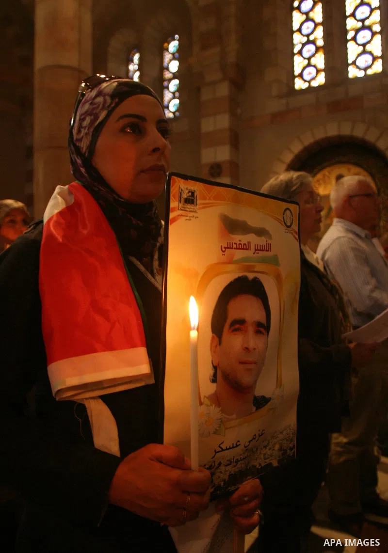 Palestinian Christians and Muslims hold pictures of incarcerated relatives during a special service at the Dominican monastery of Saint-Etienne in east Jerusalem on May 8, 2012 in solidarity with prisoners on hunger stri...