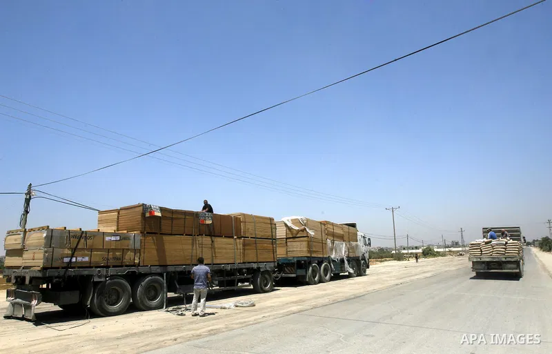 Palestinian men stand near trucks loaded with cement and building materials coming from Karem Salem crossing to Rafah in the southern Gaza Strip on 10 May 2012. Israel allowed access 250 trucks loaded with aid, for secto...
