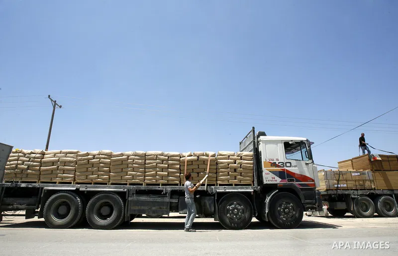 Palestinian men stand near trucks loaded with cement and building materials coming from Karem Salem crossing to Rafah in the southern Gaza Strip on 10 May 2012. Israel allowed access 250 trucks loaded with aid, for secto...