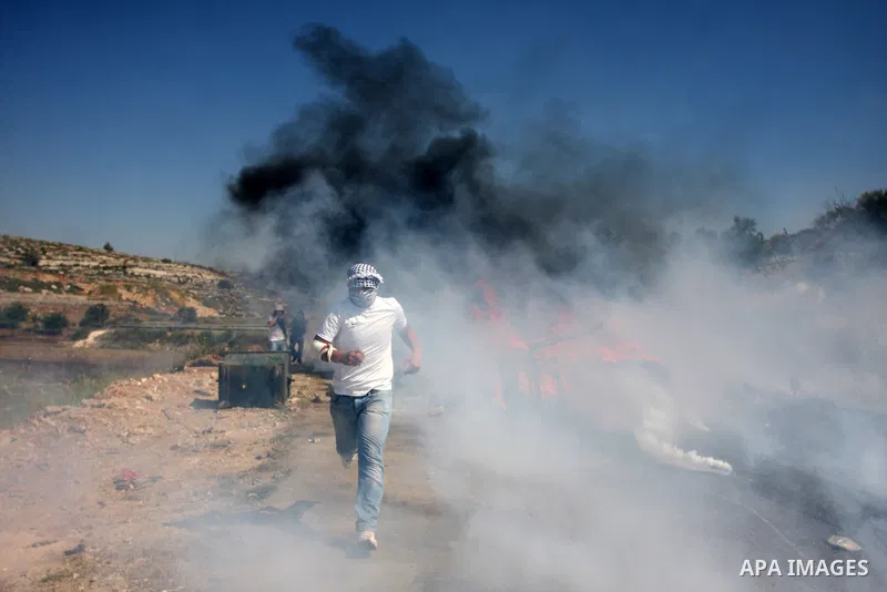 Palestinian protesters run for cover from the teargas fired by Israeli soldiers during clashes outside the Ofer Prison close to the West Bank city of Ramallah, following a demonstration in support of Palestinian prisoner...