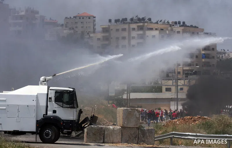 Palestinian protesters run for cover from the teargas fired by Israeli soldiers during clashes outside the Ofer Prison close to the West Bank city of Ramallah, following a demonstration in support of Palestinian prisoner...