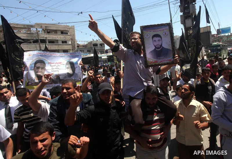 Palestinians hold up portraits of Palestinian prisoners, held in Israeli jails, and shout slogans during a demonstration in southern Gaza strip, city of Khan Younis, on May 11, 2012 in solidarity with the prisoners. At l...