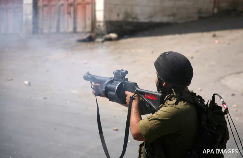 An Israeli soldier fires tear gas at stone throwing Palestinians after clashes broke out during a protest in solidarity with incarcerated Palestinians on hunger strike in Israeli jails on May 11, 2012, in the village of...