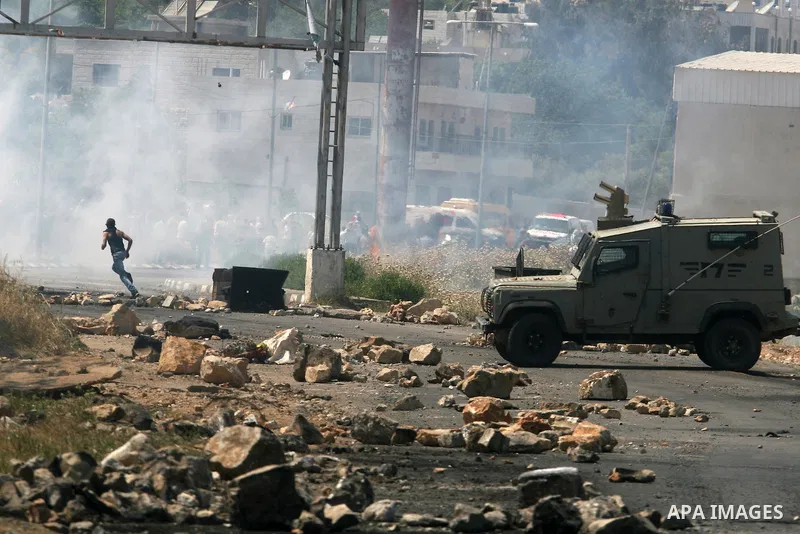 Palestinian protesters run for cover from the teargas fired by Israeli soldiers during clashes outside the Ofer Prison near the West Bank city of Ramallah on May 11, 2012 following a demonstration in support of Palestini...