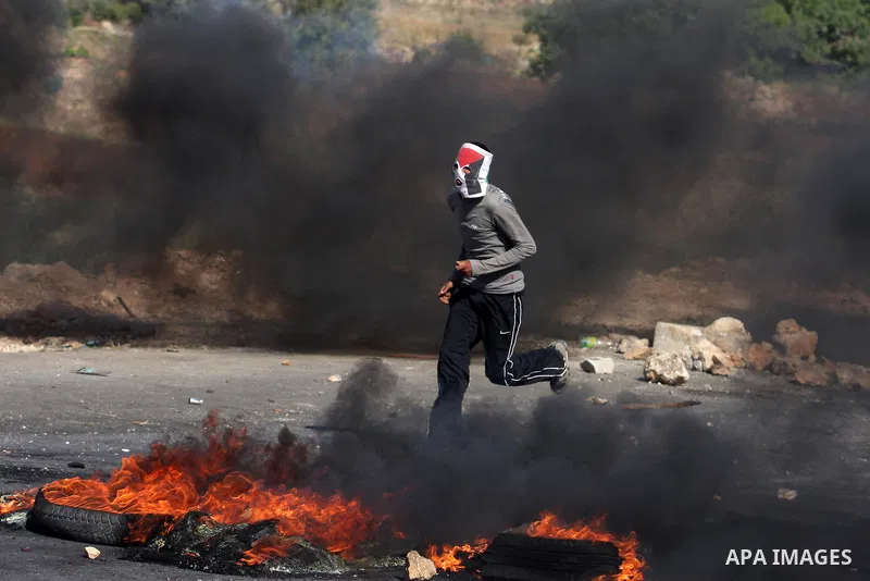 Palestinian protesters cover behind the burning tyres during clashes with Israeli soldiers outside the Ofer Prison near the West Bank city of Ramallah on May 11, 2012 following a demonstration in support of Palestinian p...