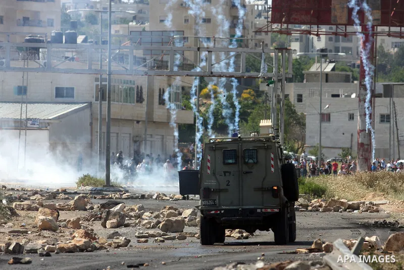 Palestinian protesters run for cover from the teargas fired by Israeli soldiers during clashes outside the Ofer Prison near the West Bank city of Ramallah on May 11, 2012 following a demonstration in support of Palestini...