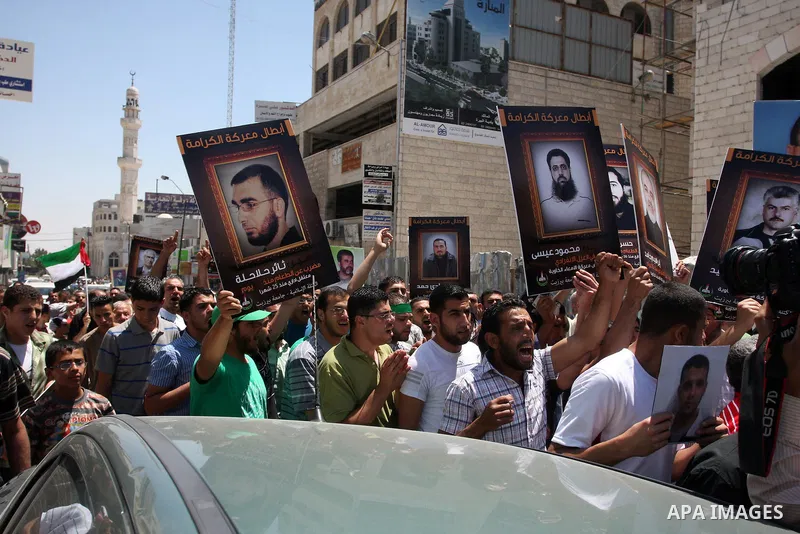 Palestinian protesters holding pictures of jailed Palestinians in Israel in the West Bank city of Ramallah, 11 May 2012, during a solidarity Rally with Palestinian prisoners in Israeli jails. The prisoners launched an op...