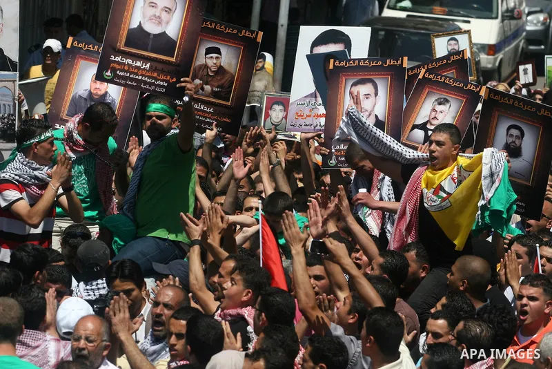 Palestinian protesters holding pictures of jailed Palestinians in Israel in the West Bank city of Ramallah, 11 May 2012, during a solidarity Rally with Palestinian prisoners in Israeli jails. The prisoners launched an op...