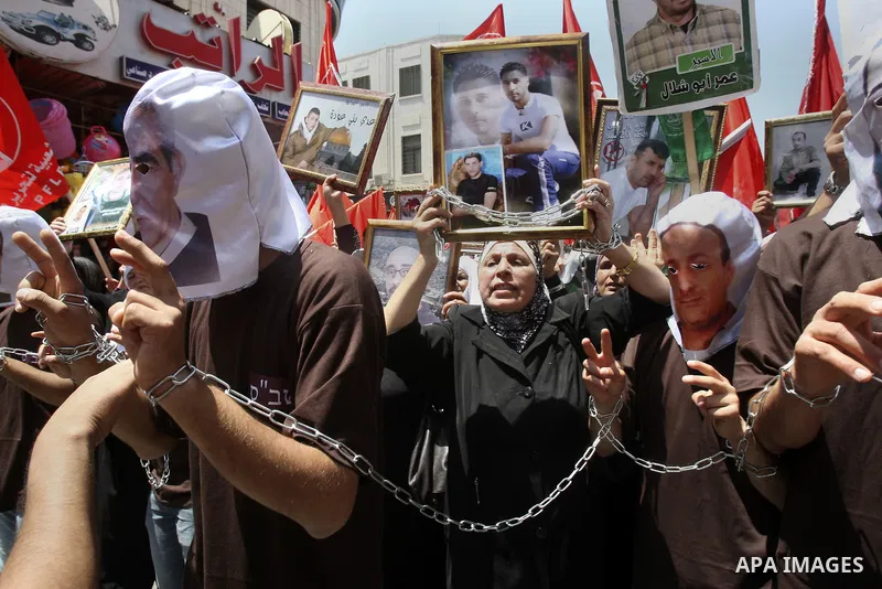 Palestinian protesters cover their faces with pictures of Palestinian prisoners during protests in the center of Nablus City , 12 May 2012 for the release of prisoners held in Israeli jails. Hundreds of Palestinians serv...