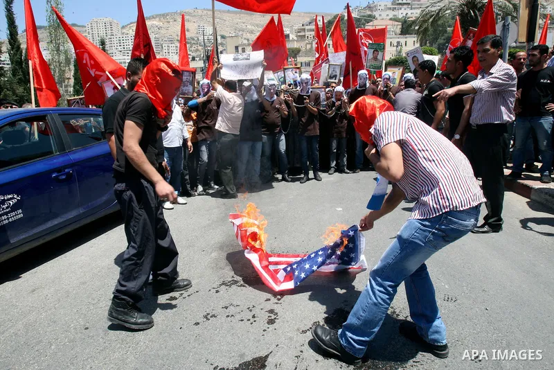 Palestinian protesters cover their faces burn Israeli and American flag during protests in the center of Nablus City , 12 May 2012 for the release of prisoners held in Israeli jails. Hundreds of Palestinians serving admi...