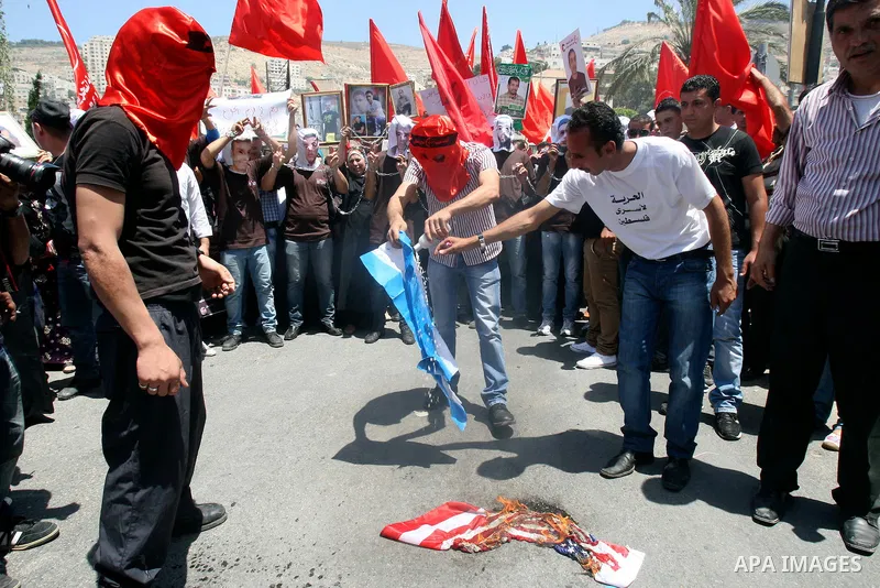 Palestinian protesters cover their faces burn Israeli and American flag during protests in the center of Nablus City , 12 May 2012 for the release of prisoners held in Israeli jails. Hundreds of Palestinians serving admi...