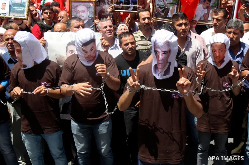 Palestinian protesters cover their faces with pictures of Palestinian prisoners during protests in the center of Nablus City , 12 May 2012 for the release of prisoners held in Israeli jails. Hundreds of Palestinians serv...