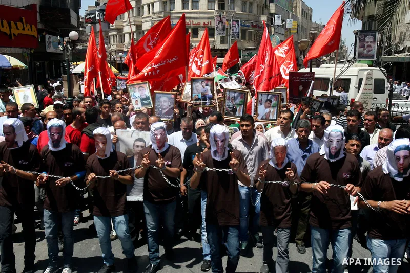 Palestinian protesters cover their faces with pictures of Palestinian prisoners during protests in the center of Nablus City , 12 May 2012 for the release of prisoners held in Israeli jails. Hundreds of Palestinians serv...