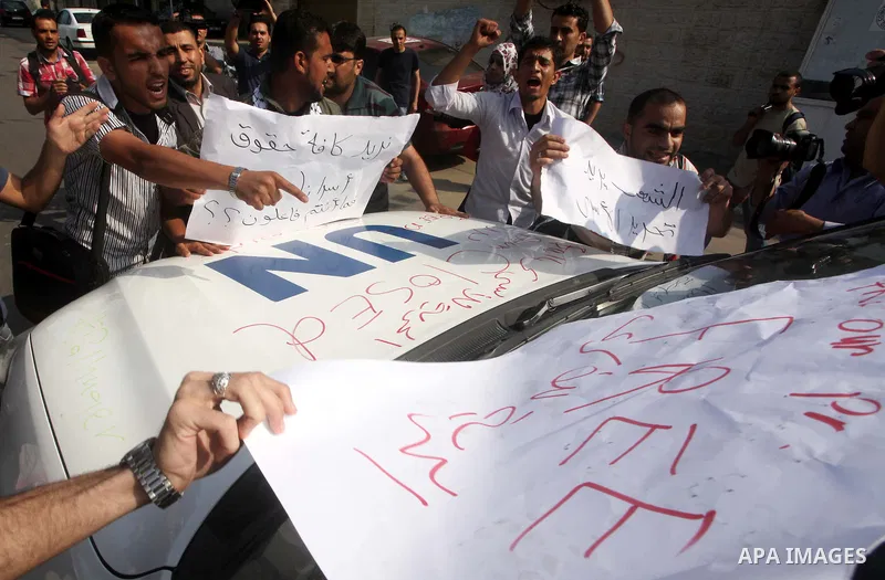 A Palestinian protester holds up a sign in front of a U.N. vehicle during a protest in Gaza City, to show solidarity with Palestinian prisoners held in Israeli jails, May 13, 2012. Hundreds of Palestinians on hunger stri...