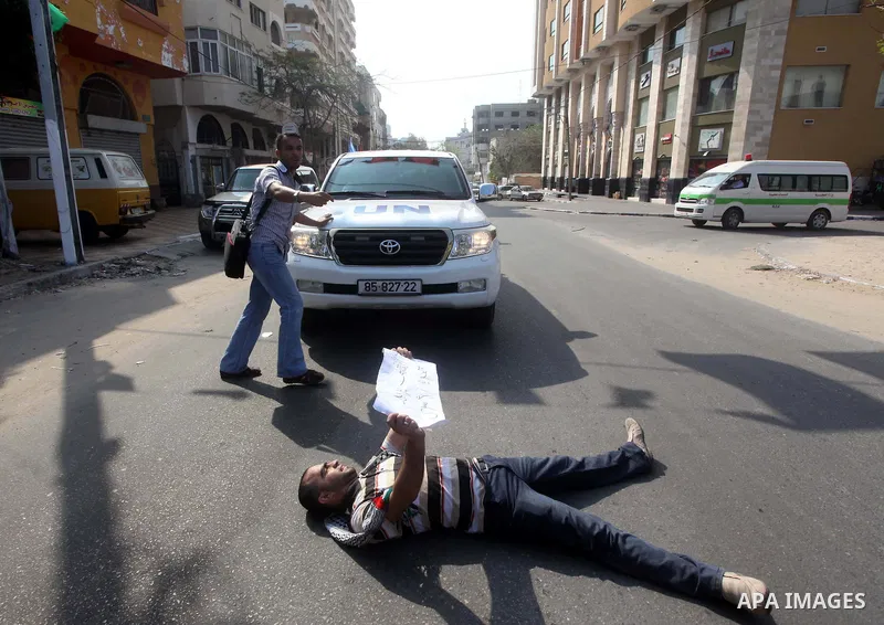 A Palestinian protestor lies on the ground during a protest in front of the Red Cross headquarters in Gaza City to show solidarity with Palestinian prisoners held in Israeli jails May 13, 2012. Hundreds of Palestinians o...