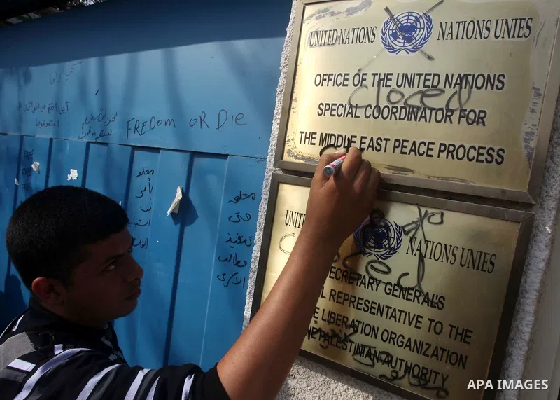 A Palestinian youth writes on the plaque of the Office of the United Nations Special Coordinator (UNSCO) headquarters in Gaza, as they forced the offices to close for two hours in solidarity with over 1,550 prisoners obs...