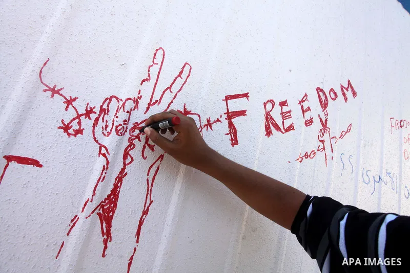 A Palestinian writes outside the headquarters of the International Committee of the Red Cross (ICRC) in Gaza as protestors forced the offices to close for two hours in solidarity with over 1,550 prisoners observing a hun...