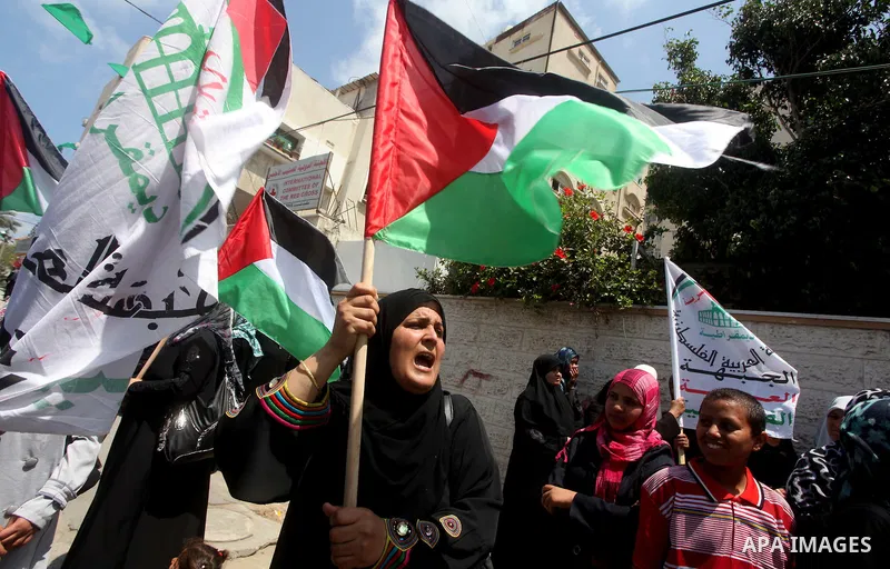 Palestinian protesters hold up signs outside the headquarters of the International Committee of the Red Cross (ICRC) during a protest in Gaza City, to show solidarity with Palestinian prisoners held in Israeli jails, May...