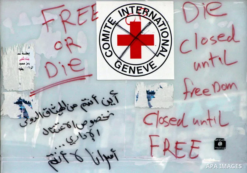 Palestinian write slogans, outside the headquarters of the International Committee of the Red Cross (ICRC) in Gaza as protestors forced the offices to close for two hours in solidarity with over 1,550 prisoners observing...