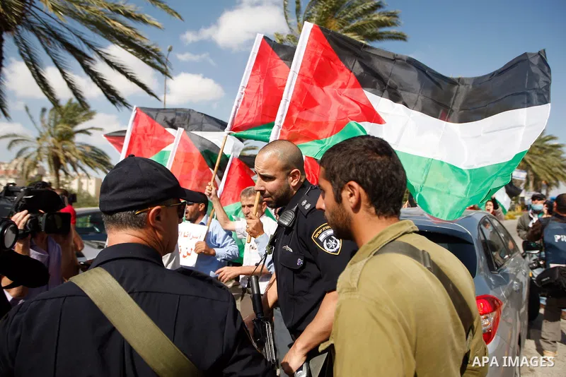 Dozens of Palestinian, Israeli and foreign activists hold Palestinian flags as they gather near the Maale Adumim settlement in West Bank on May 13, 2012 during a demonstration in support of Palestinian prisoners observin...