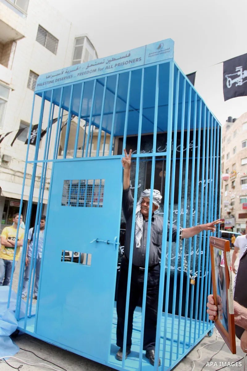 A Palestinian man gestures from inside a mock prison cell during a rally in the West Bank city of Ramallah, in support of Palestinian prisoners on a hunger strike in Israeli jails May 14, 2012. One in three of the 4,800...