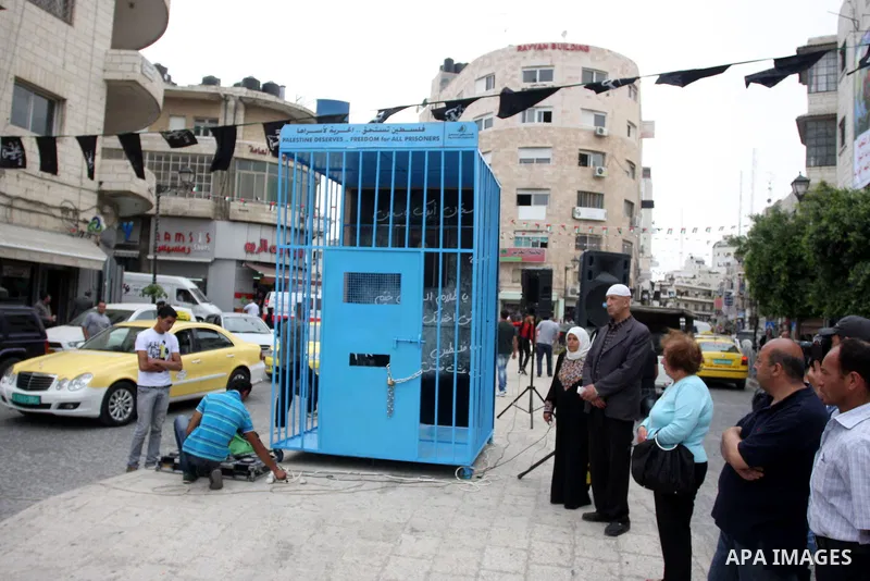 A Palestinian man gestures from inside a mock prison cell during a rally in the West Bank city of Ramallah, in support of Palestinian prisoners on a hunger strike in Israeli jails May 14, 2012. One in three of the 4,800...