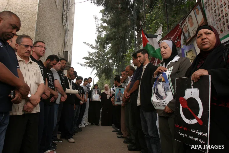 Palestinian protesters hold pictures of Palestinian prisoners during a visit to a protest tent outside the International Committee of the Red Cross (ICRC) offices in East Jerusalem, as the protestors join the hunger stri...