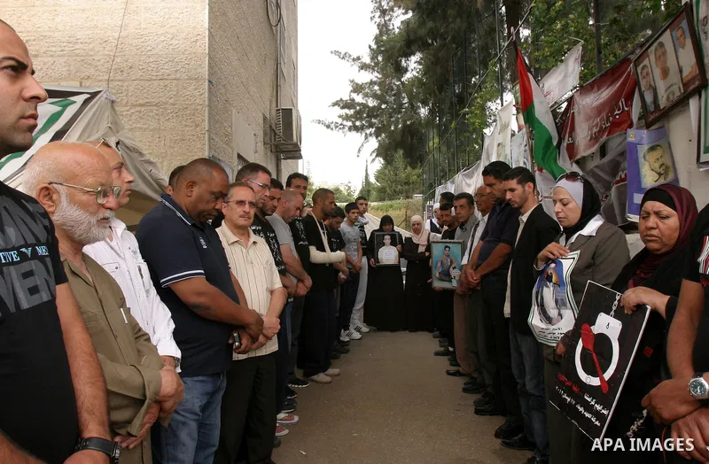 Palestinian protesters hold pictures of Palestinian prisoners during a visit to a protest tent outside the International Committee of the Red Cross (ICRC) offices in East Jerusalem, as the protestors join the hunger stri...