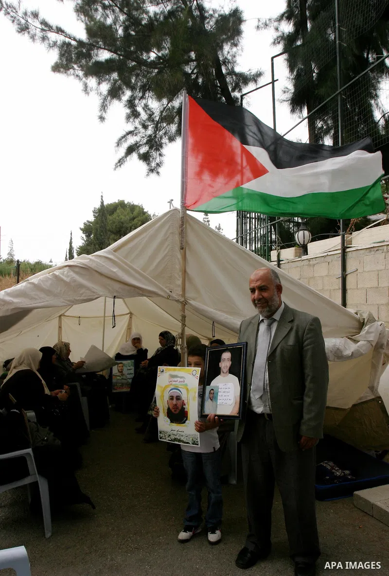 Palestinian protesters hold pictures of Palestinian prisoners during a visit to a protest tent outside the International Committee of the Red Cross (ICRC) offices in East Jerusalem, as the protestors join the hunger stri...