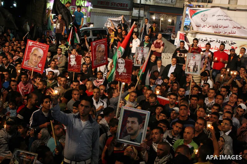 Palestinians hold pictures of prisoners and Palestinian flags as they celebrate the end of a prisoners' hunger strike in Israeli jails, in the West Bank city of Ramallah, Monday, May 14, 2012. Hundreds of Palestinian pri...