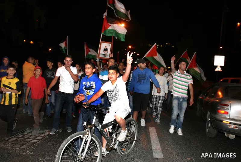 Palestinian hold national flags during celebrate after the signing of a deal to end the prisoners hunger strike in Jerusalem on 14 May 2012. Israel and Palestinian signed an agreement 14 May ending a mass hunger strike b...
