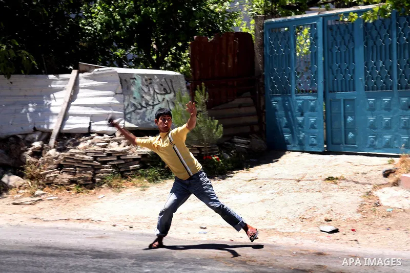 Palestinian boys throw stones towards Israeli soldiers deployed at the entrance of the al-Aroub Palestinian refugee camp, just north the West Bank town of Hebron on May 15, 2012, as Palestinians mark Nakba day, which com...