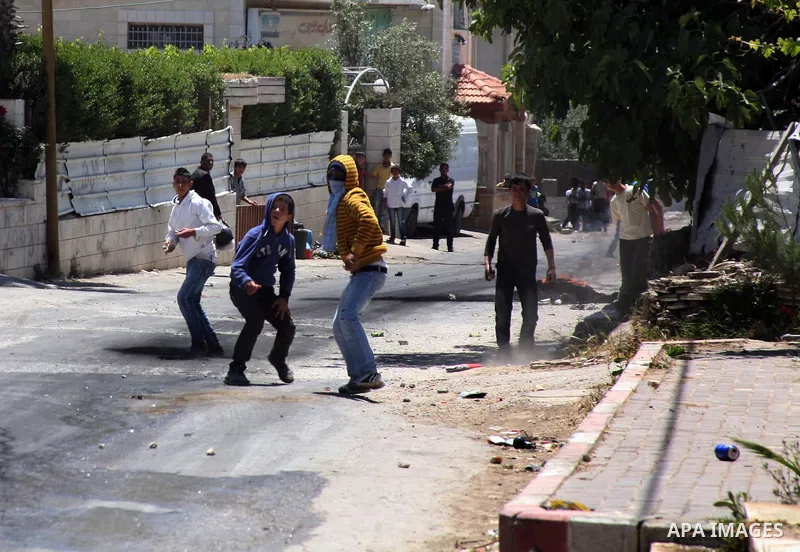 Palestinian boys throw stones towards Israeli soldiers deployed at the entrance of the al-Aroub Palestinian refugee camp, just north the West Bank town of Hebron on May 15, 2012, as Palestinians mark Nakba day, which com...