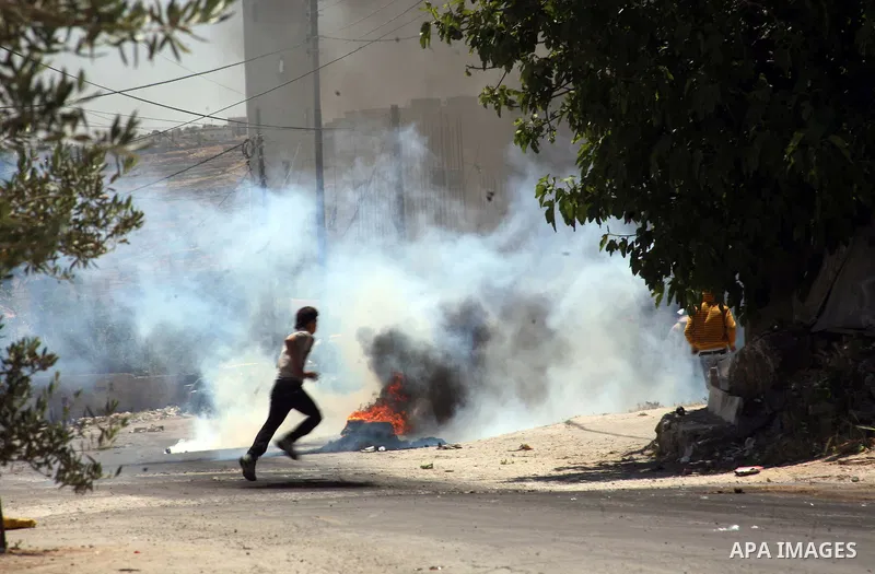 Palestinian boys throw stones towards Israeli soldiers deployed at the entrance of the al-Aroub Palestinian refugee camp, just north the West Bank town of Hebron on May 15, 2012, as Palestinians mark Nakba day, which com...