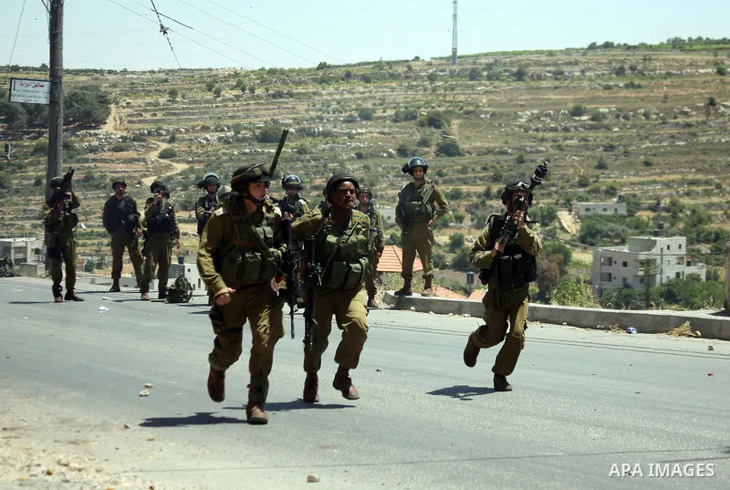 Israeli soldiers fire teargas, towards Palestinian stone throwers deployed at the entrance of the al-Aroub Palestinian refugee camp, just north the West Bank town of Hebron on May 15, 2012, as Palestinians mark Nakba day...