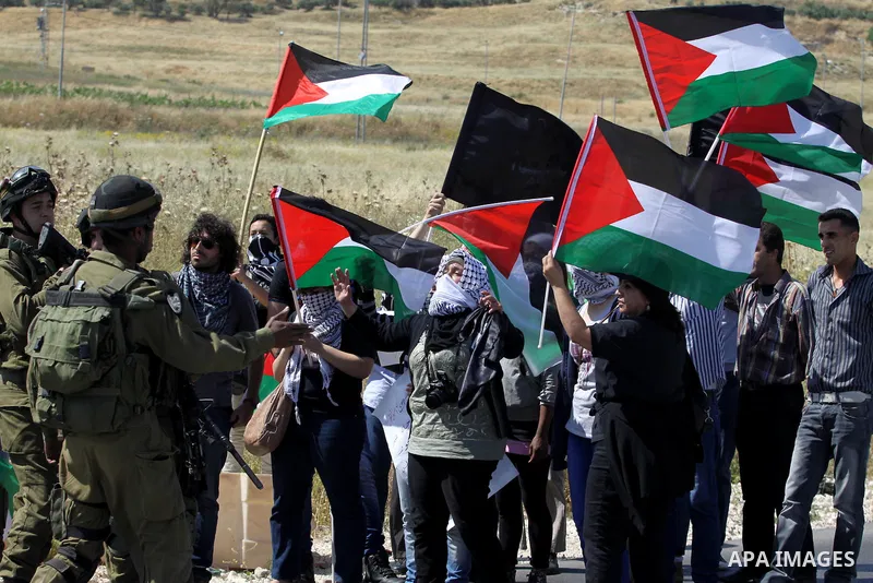 Israeli soldiers stand face to Palestinian and foreign activists who hold Palestinian flags during a demonstration marking the 64th anniversary of the 'Nakba' ('catastrophe'), at the Hawara checkpoint near the West Bank...