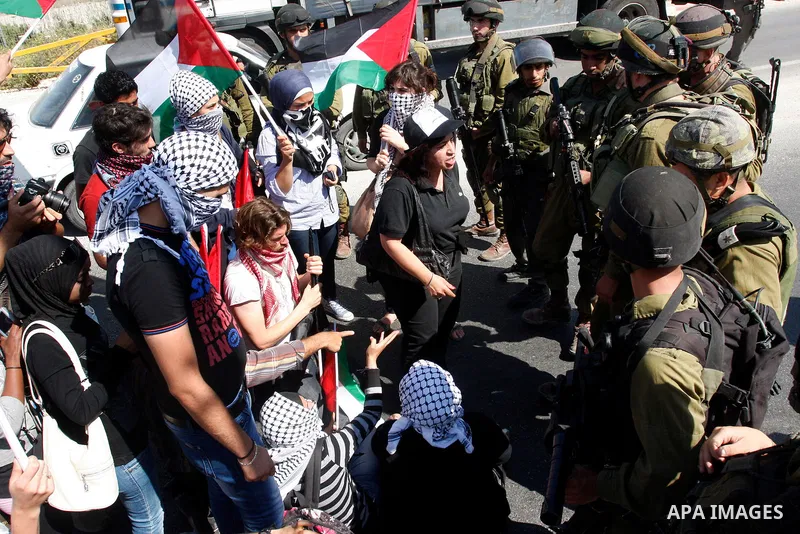Israeli soldiers stand face to Palestinian and foreign activists who hold Palestinian flags during a demonstration marking the 64th anniversary of the 'Nakba' ('catastrophe'), at the Hawara checkpoint near the West Bank...