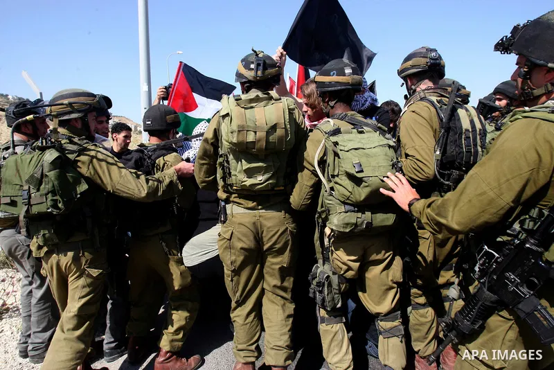 Israeli soldiers stand face to Palestinian and foreign activists who hold Palestinian flags during a demonstration marking the 64th anniversary of the 'Nakba' ('catastrophe'), at the Hawara checkpoint near the West Bank...