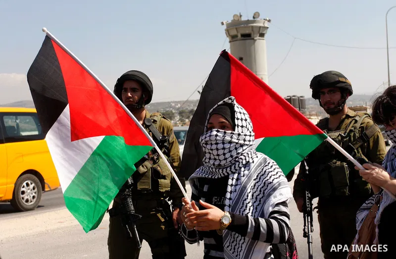 Israeli soldiers stand face to Palestinian and foreign activists who hold Palestinian flags during a demonstration marking the 64th anniversary of the 'Nakba' ('catastrophe'), at the Hawara checkpoint near the West Bank...