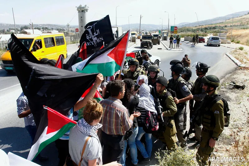 Israeli soldiers stand face to Palestinian and foreign activists who hold Palestinian flags during a demonstration marking the 64th anniversary of the 'Nakba' ('catastrophe'), at the Hawara checkpoint near the West Bank...